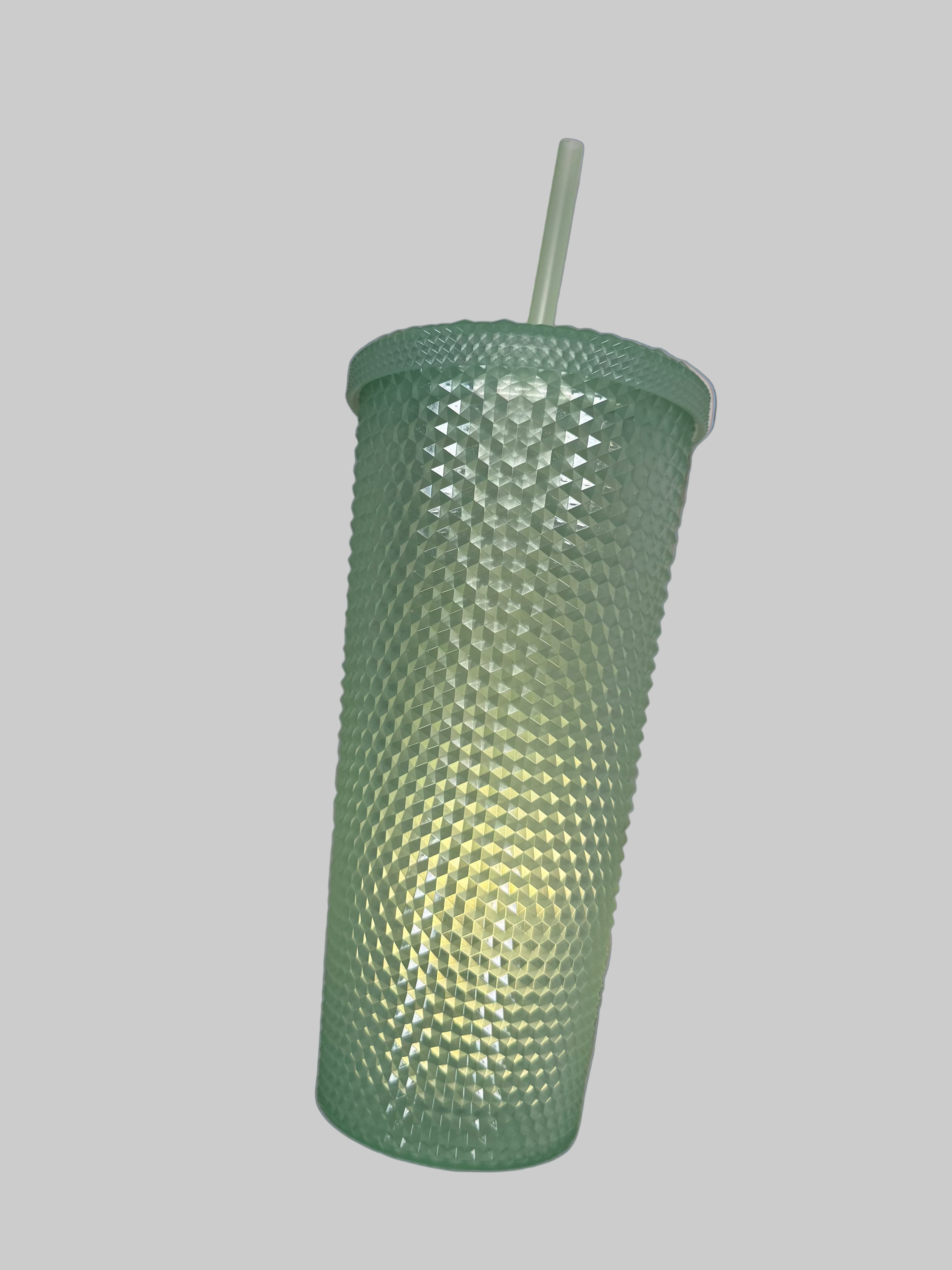 Green textured tumbler with a straw on a light blue blanket